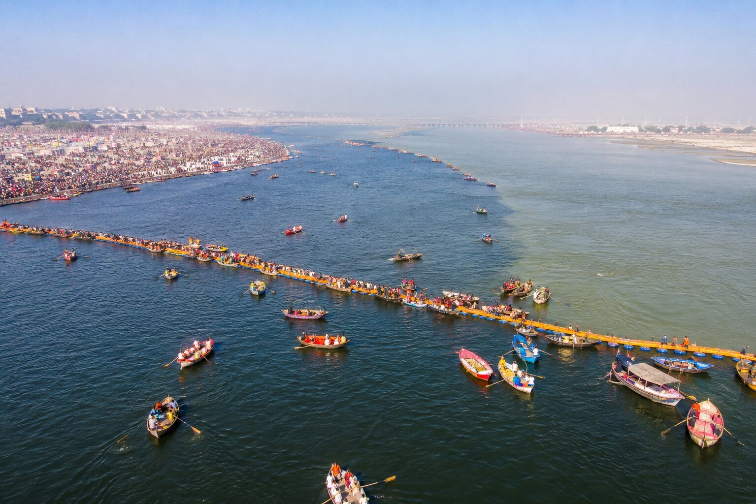 Triveni Sangam — aerial view of the sacred confluence with pontoon bridge and pilgrim boats, Prayagraj